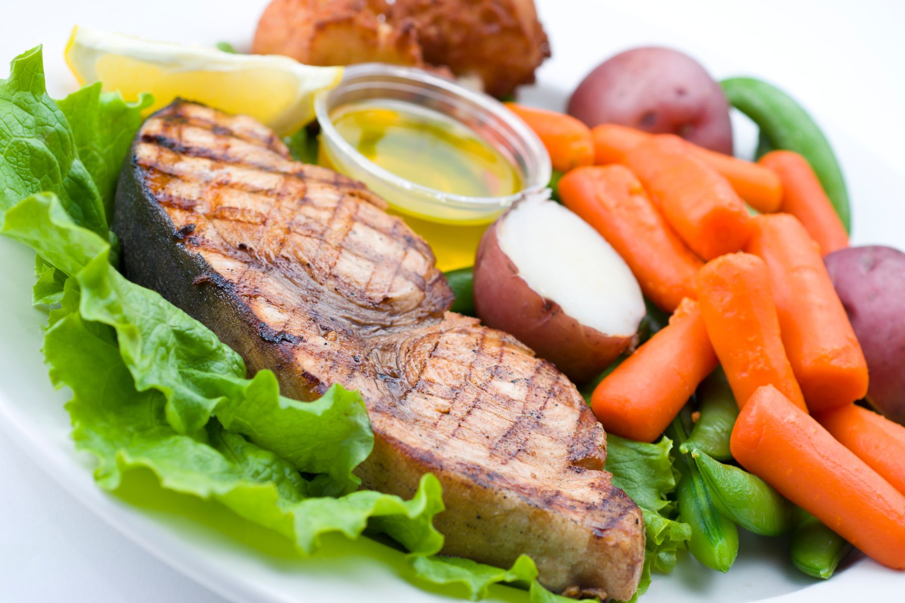 Plato con verduras y otros alimentos (zanahorias, patata, lechuga judías...) y un apetitoso pez espada